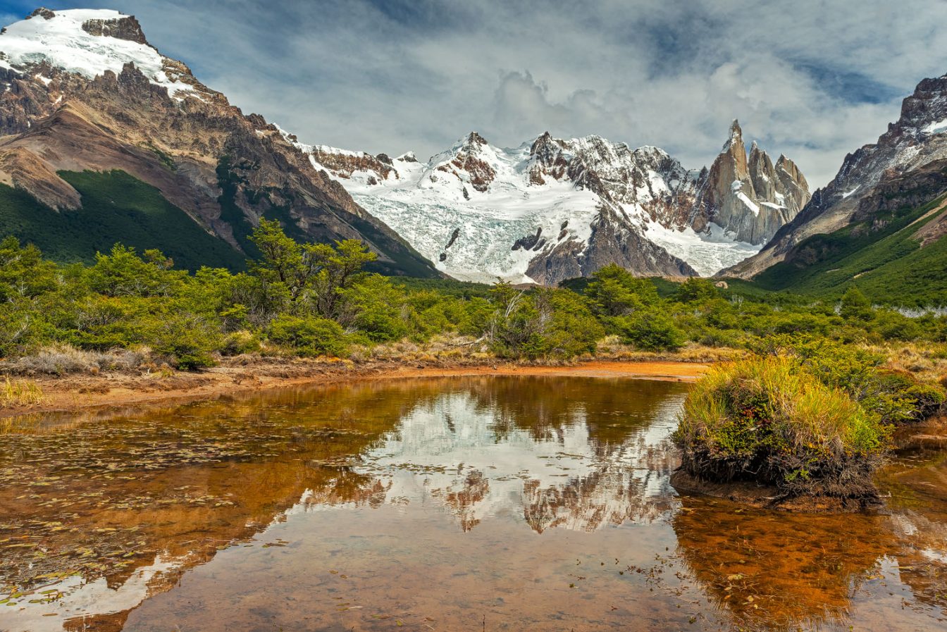 Landscape photography of the Cerro Torre mountain range reflecting in a small pond seen from the trekking trail to the base camp