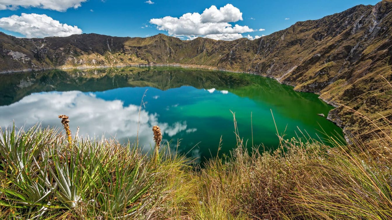 Panoramic photography of the emerald green lake located at the bottom the Quilotoa volcanic caldera.